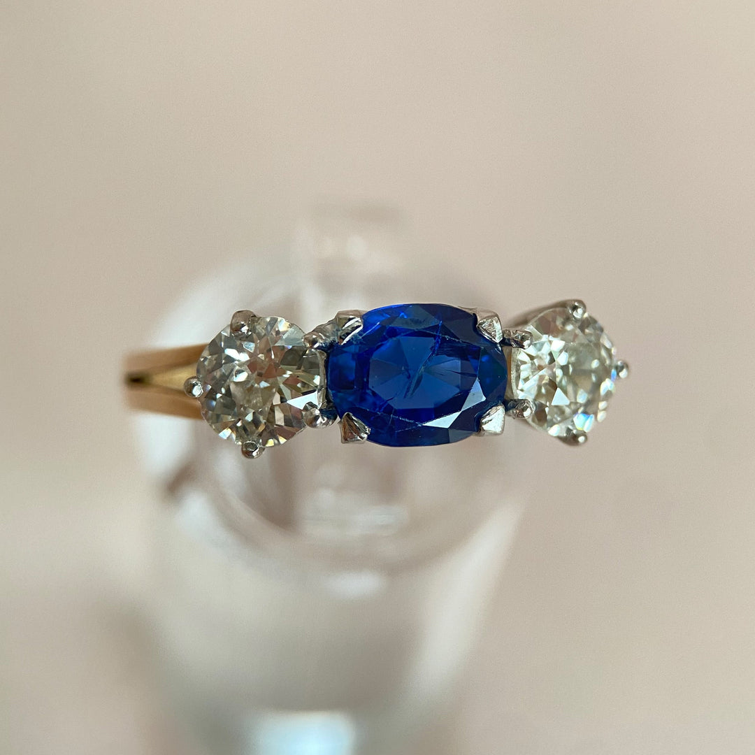 Moderner Ring aus den 1990ern mit 1,5 ct blauem Saphir im facettierten Ovalschliff und zwei alten Diamantschliffen im klassischen Rot‑ und Weißgold‑Design