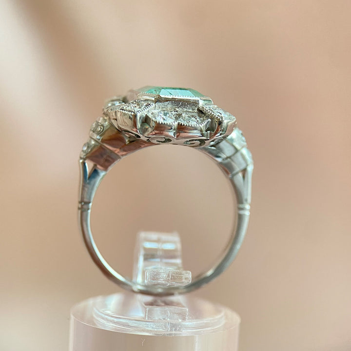 Gesamtaufnahme des Platinrings mit Smaragd und Diamanten auf neutralem Hintergrund, hochwertige Produktdarstellung