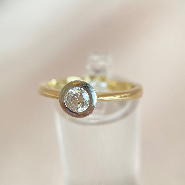 Seitenansicht des eleganten Gelb- und Weißgoldrings mit Diamant in Zargenfassung