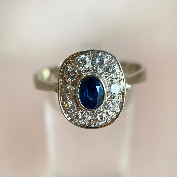 Vintage-Weißgoldring 585 aus den 1980ern mit dunkelblauem facettierten Oval-Saphir und zehn Diamanten im Rundschliff, klassischer Entourage-Stil