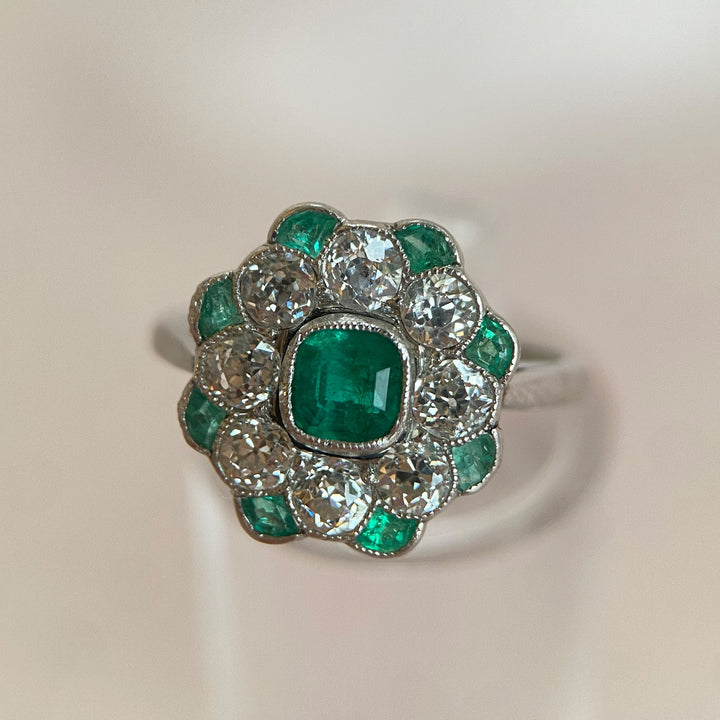 Detailaufnahme des zentralen facettierten Kissenschliff-Smaragds im Platinring mit Gelbgoldfassung, tiefgrüne Farbe sichtbar