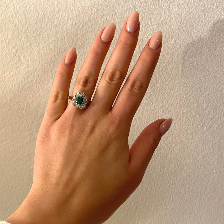 Tragefoto: Weißgold‑Ring mit Smaragd und Diamanten am Finger getragen, zeigt Größe, Proportion und elegante Wirkung