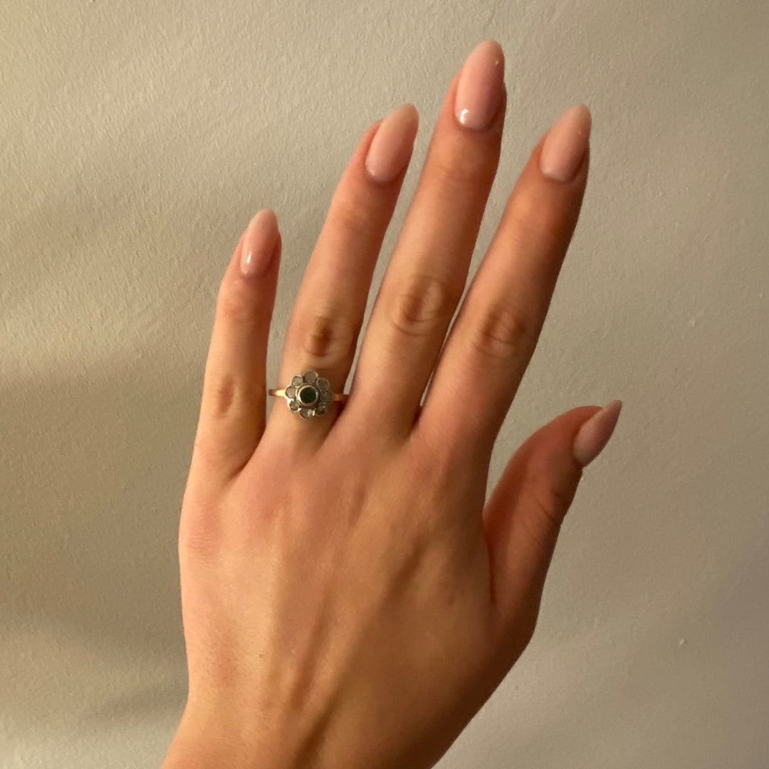Tragefoto: Vintage‑Weißgoldring mit Smaragd und funkelnden Diamanten am Finger getragen, zeigt Größe und edle Wirkung