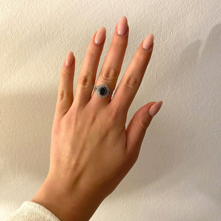 Tragefoto: Weißgoldring mit dunkelblauem Saphir und Diamanten am Finger getragen, elegante Wirkung sichtbar