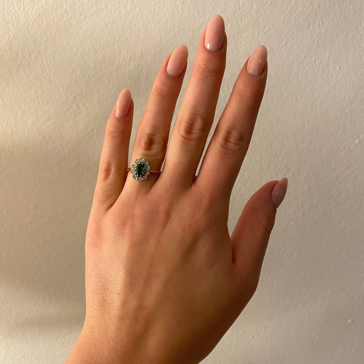 Tragefoto: Gelb‑ und Weißgoldring mit grünem Turmalin und Diamanten am Finger getragen, elegante Wirkung erkennbar