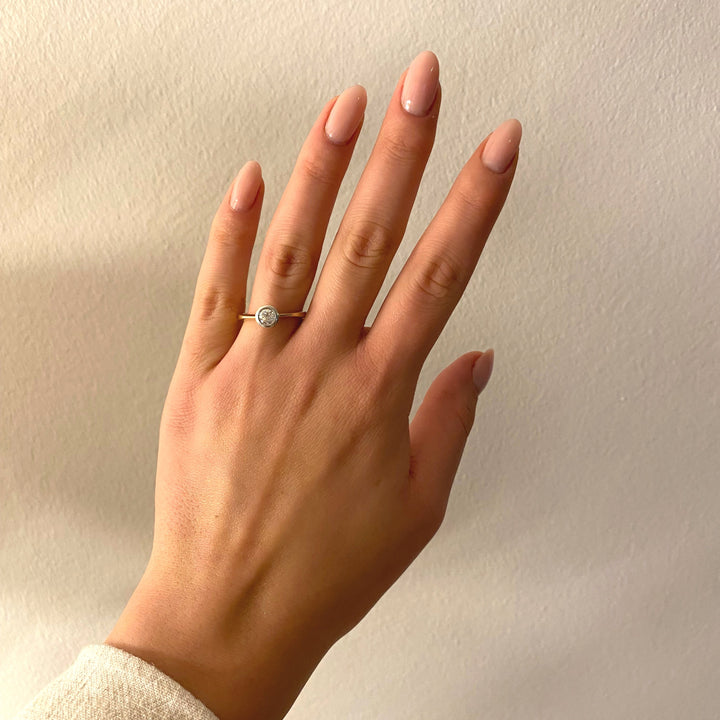 Gelb- und Weißgoldring mit Brillant an Hand/Display – edler Vintage-Schmuckstil