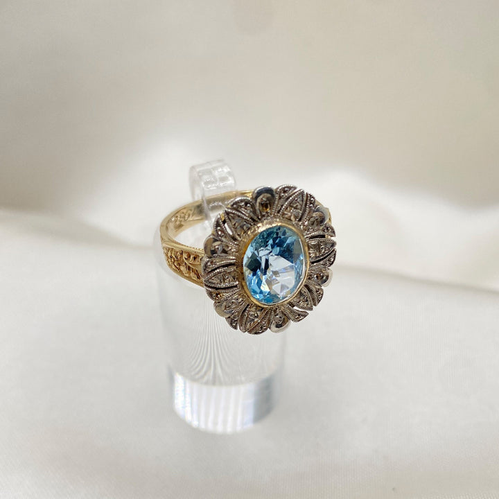 Produktfoto des Gelbgoldrings mit blauem Topas und Diamanten auf neutralem Hintergrund, zeitlose Eleganz sichtbar