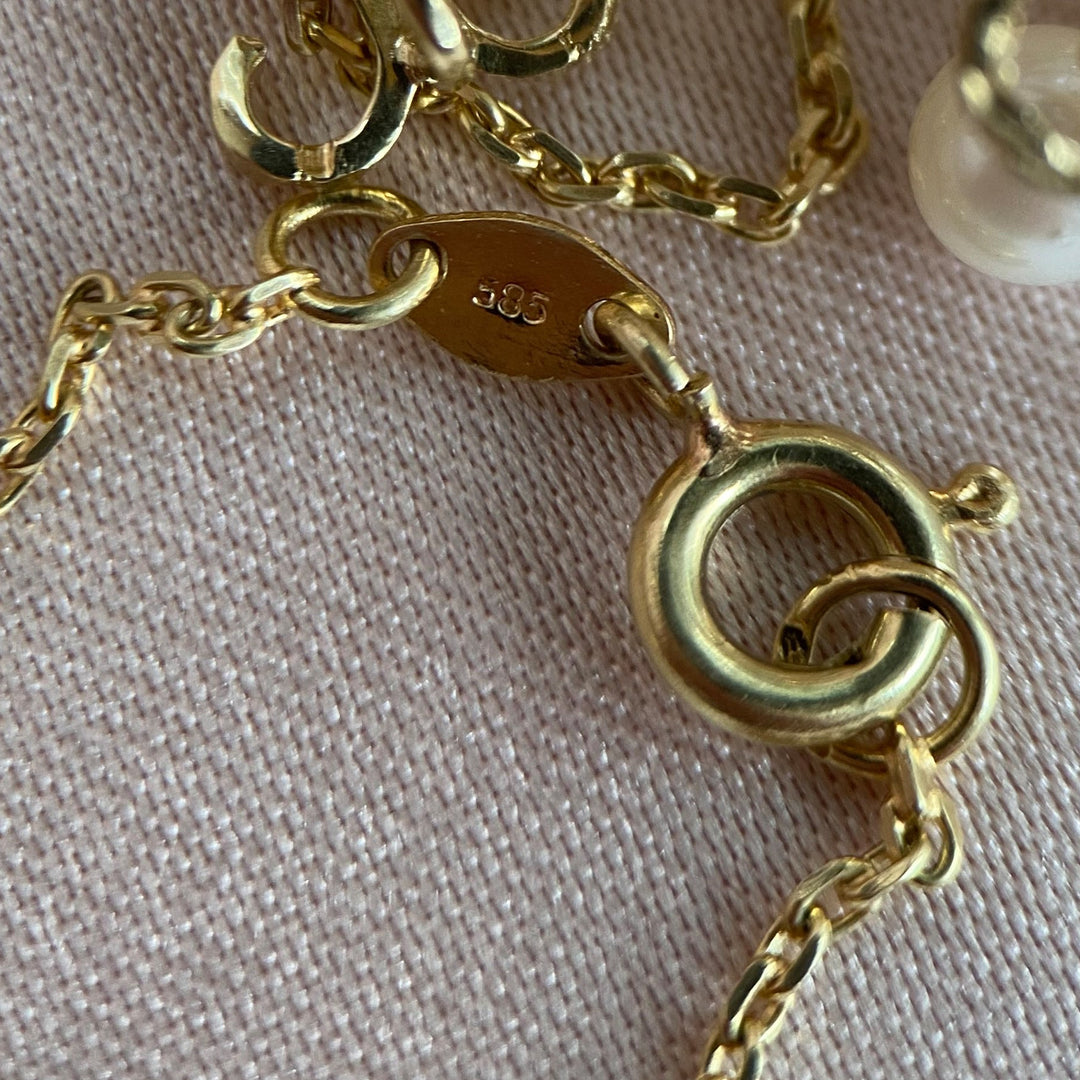 Makroaufnahme der Fassungsdetails des Chalcedons und der Perlen im Anhänger aus Gelbgold, hochwertige Handwerkskunst erkennbar