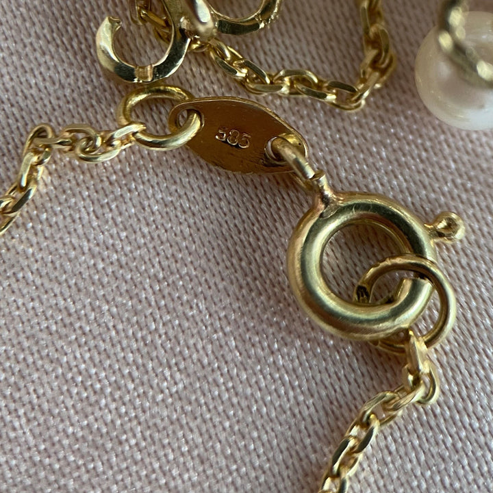 Makroaufnahme der Fassungsdetails des Chalcedons und der Perlen im Anhänger aus Gelbgold, hochwertige Handwerkskunst erkennbar