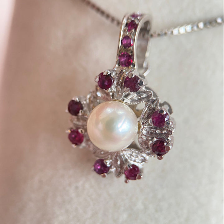 Nahaufnahme der zwölf intensiv roten Rubine im Rondenschliff im Clip‑Pendant, präzise Krappen‑ und Körnerfassungen deutlich sichtbar