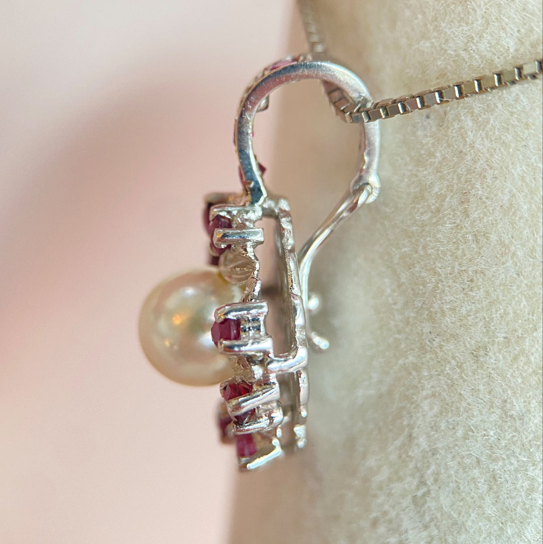 Seitenansicht des Pendants mit Blick auf Weißgold‑Profil und die Edelsteinpositionen der Rubine und Perle