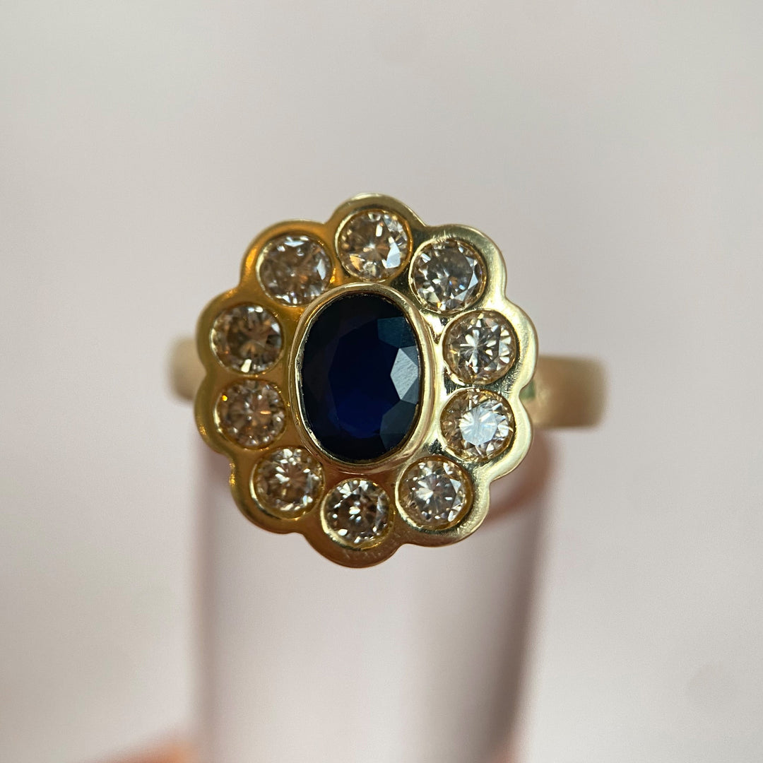 Gelbgoldring mit dunkelblauem Saphir und Diamanten in klassischer Entourage‑Fassung, edles Vintage‑Design