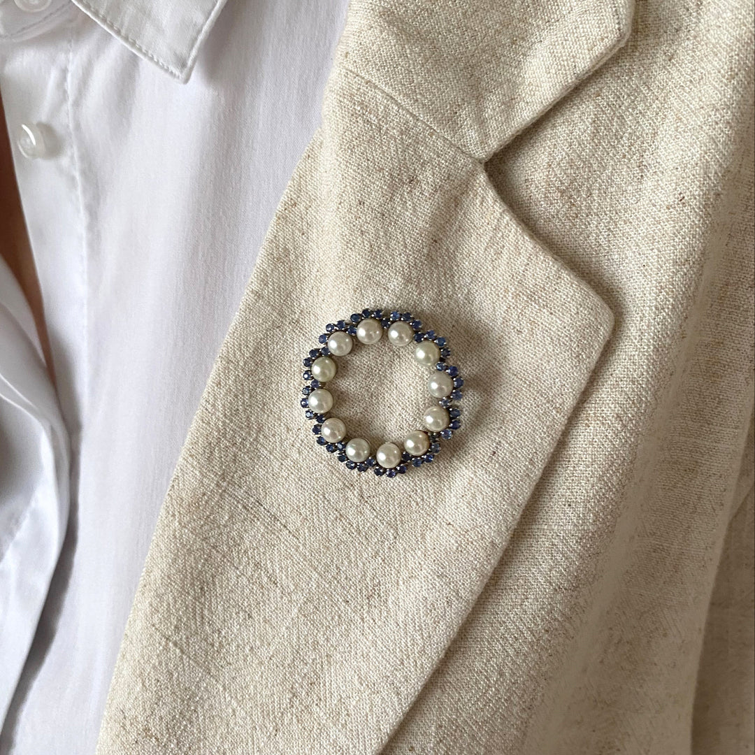 Detailansicht der Weißgold-Brosche mit Krappenfassungen, leuchtend blauen Saphiren und feinem Lüster der Akoya-Perlen.