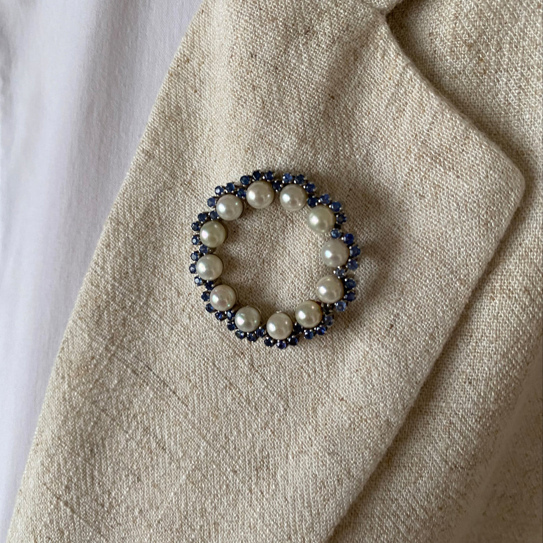 Detailansicht der Weißgold-Brosche mit Krappenfassungen, leuchtend blauen Saphiren und feinem Lüster der Akoya-Perlen.