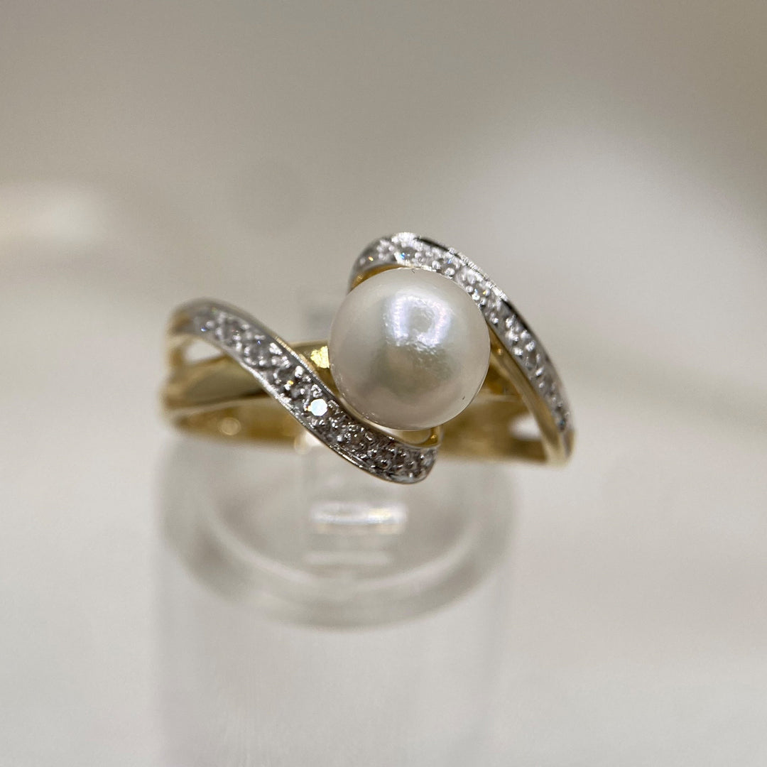 Detailaufnahme der Salzwasser-Zuchtperle mit sanftem Lüster und umlaufendem Diamantbesatz.