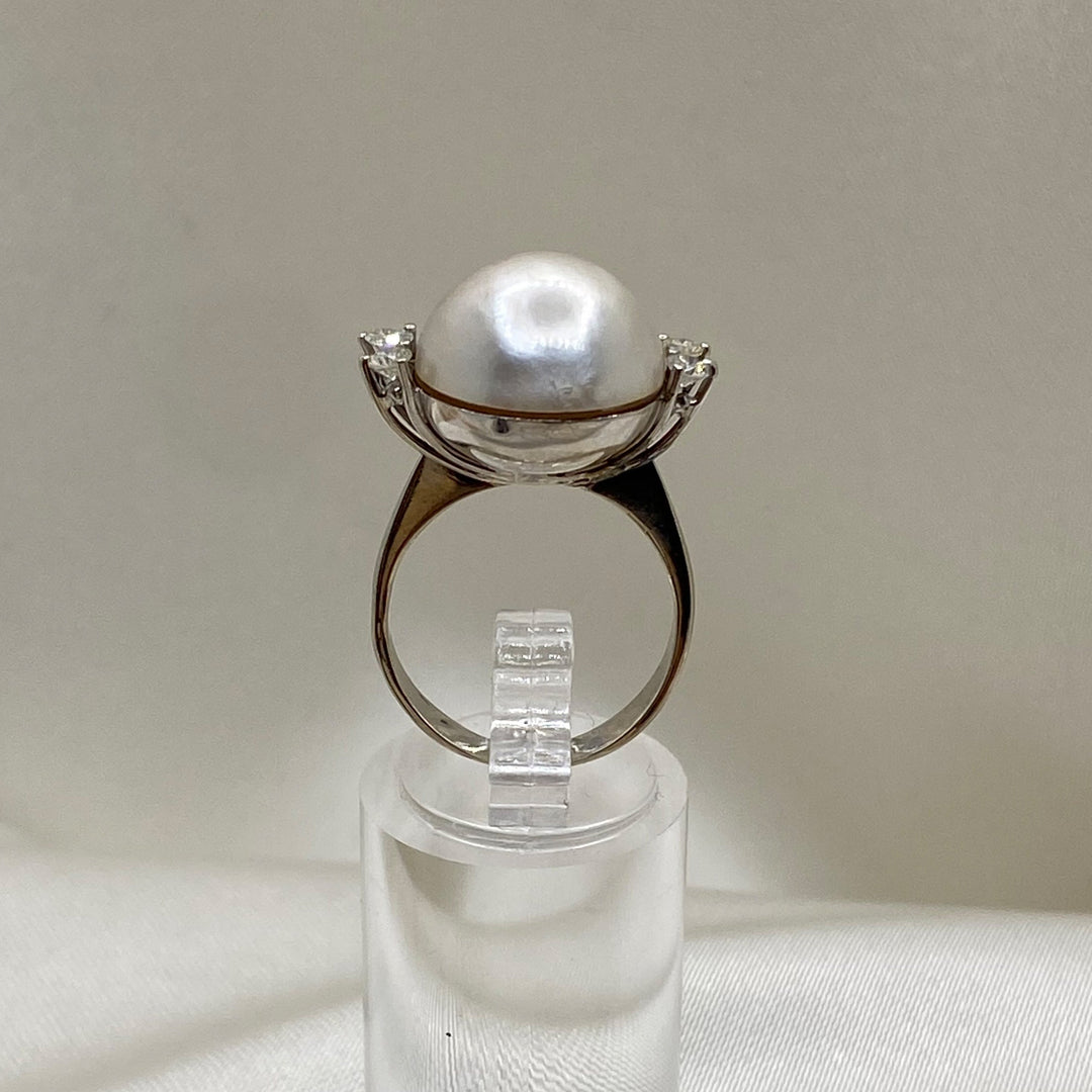 Profilansicht des stehenden Weißgoldrings mit erhöhter Mabe-Perlenfassung und seitlich gefassten Diamanten.