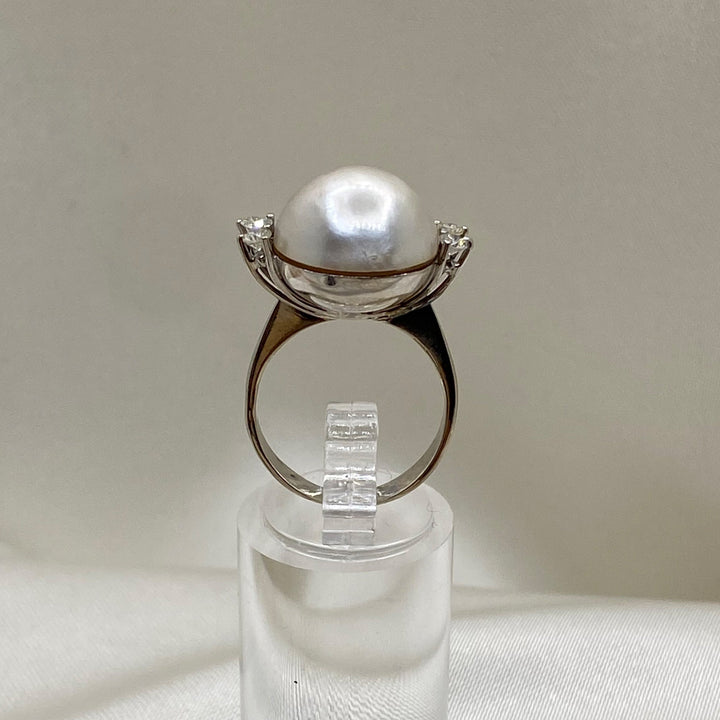 Profilansicht des stehenden Weißgoldrings mit erhöhter Mabe-Perlenfassung und seitlich gefassten Diamanten.