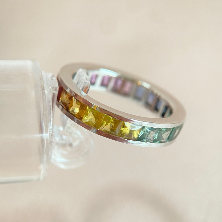 Rechte Seitenansicht des 18-karätigen Weißgoldrings mit rot-, orange- und gelbfarbenen Saphiren in Kanalfassung.