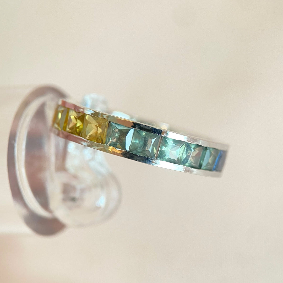 Linke Seitenansicht des Weißgoldrings mit lila-, blau- und grünfarbenen Saphiren im Prinzessschliff.