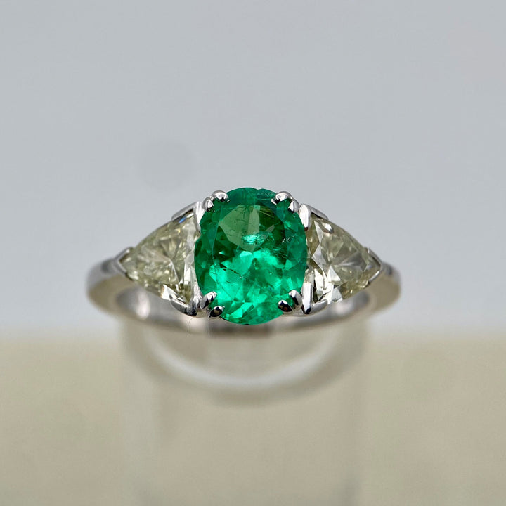 Weißgoldring aus 750er Gold mit 1,53 ct Smaragd im Ovalschliff und zwei Trilliant-Diamanten in Krappenfassungen.