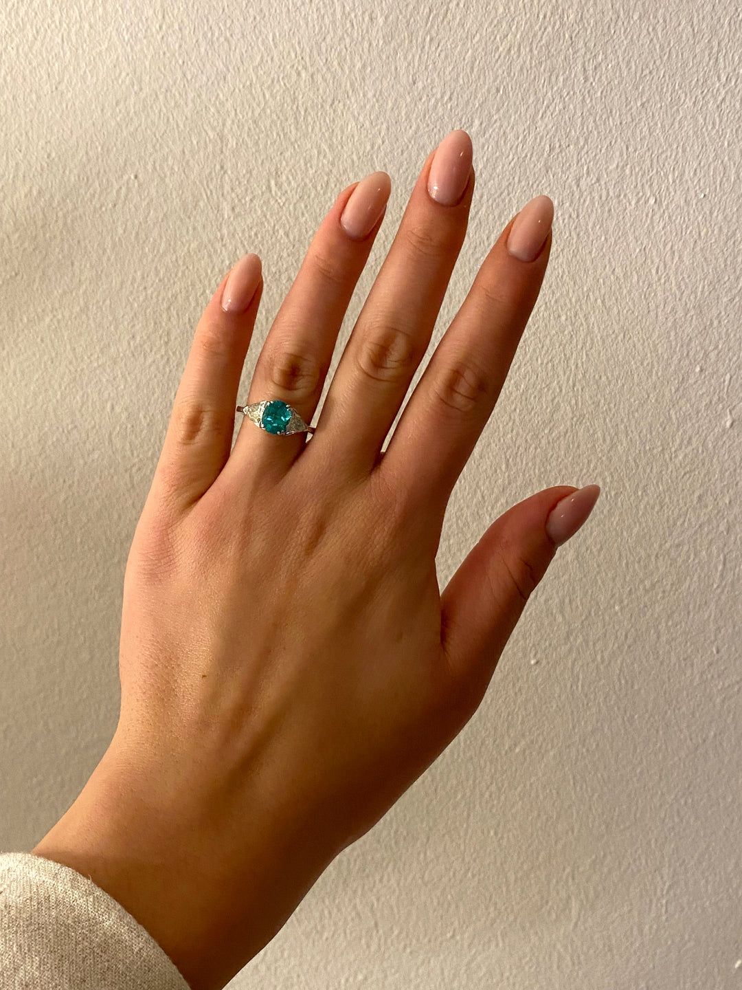 Getragener Weißgoldring mit intensiv grünem Smaragd und funkelnden Trilliant-Diamanten – harmonische Wirkung am Finger.