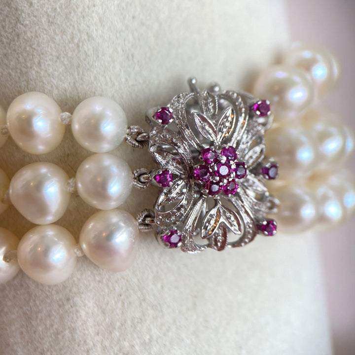 Detailaufnahme des Weißgoldarmbands mit Fokus auf einzelne Süßwasser-Zuchtperlen und einen violett-rötlichen Saphir in Krappenfassung.